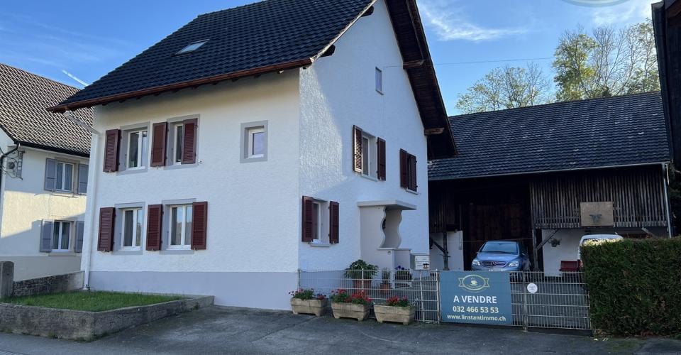 Maison villageoise avec une grande grange et un grand jardin.